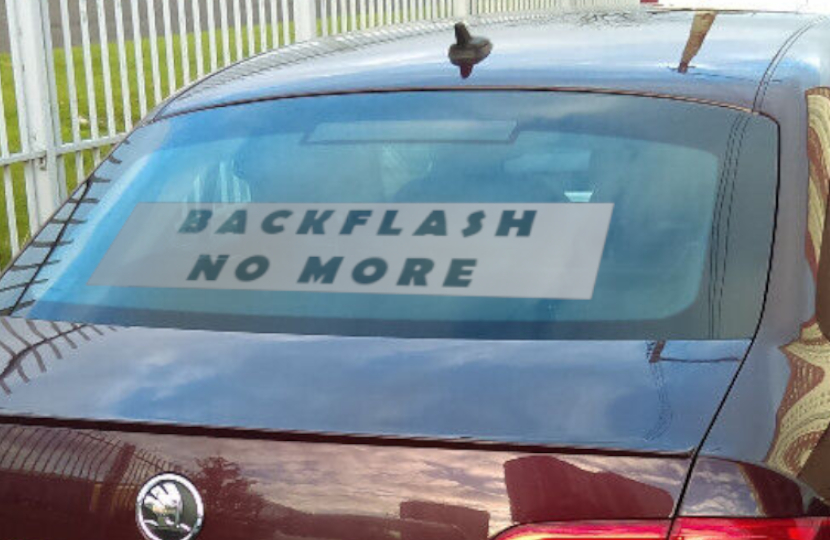 Image of car with a banner in rear window reading "Backflash No More"